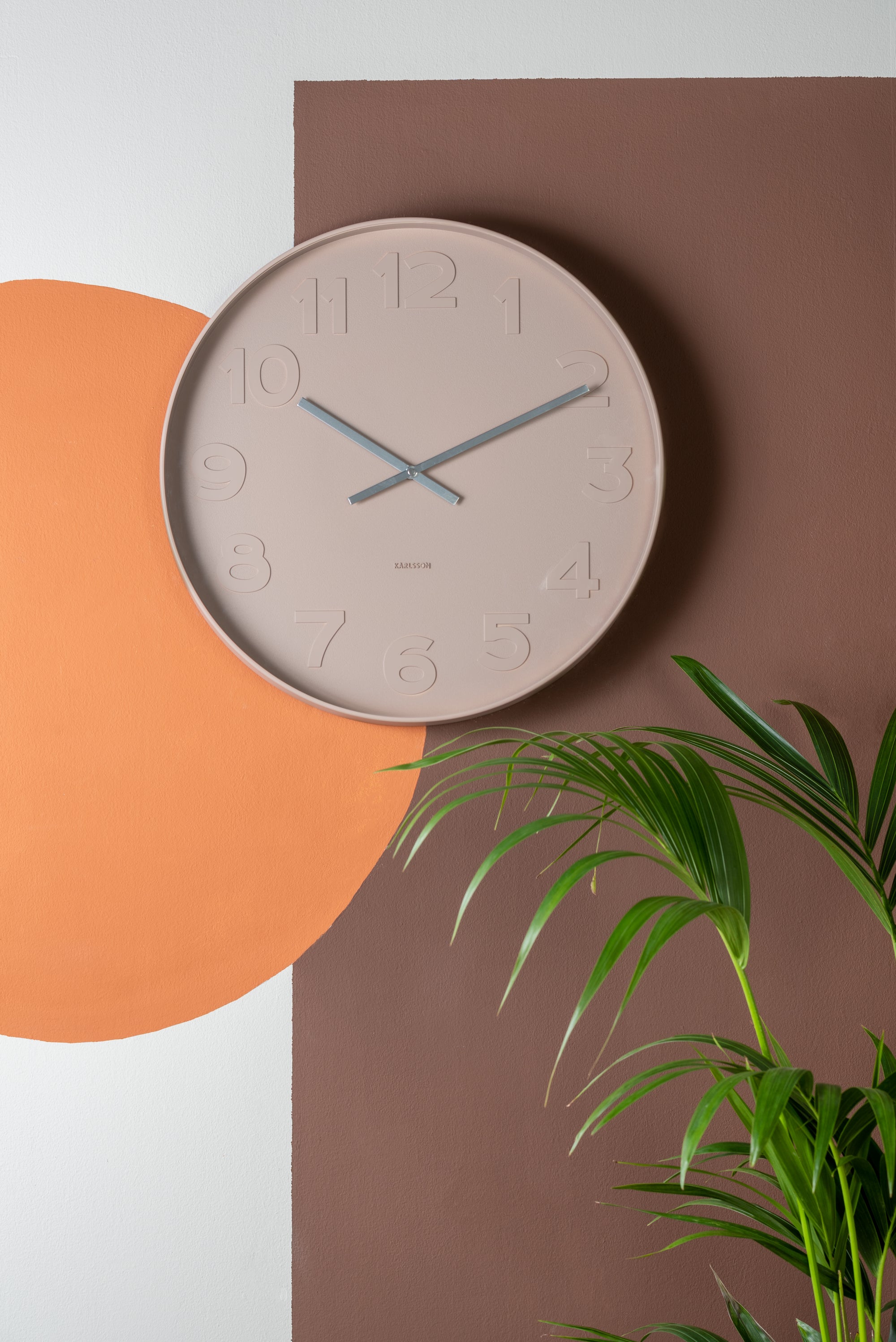 Brown wall clock hung on brown, orange and white wall