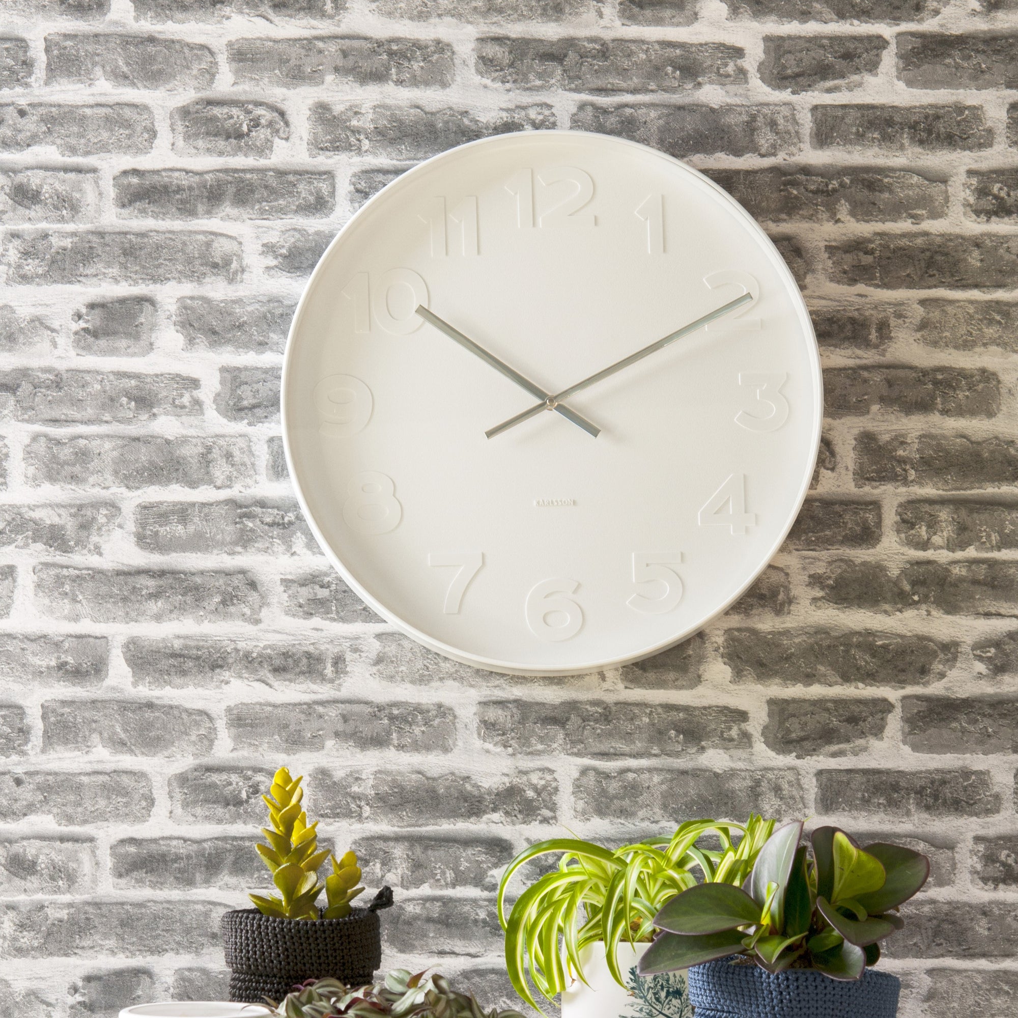 White wall clock hung on grey brick wall